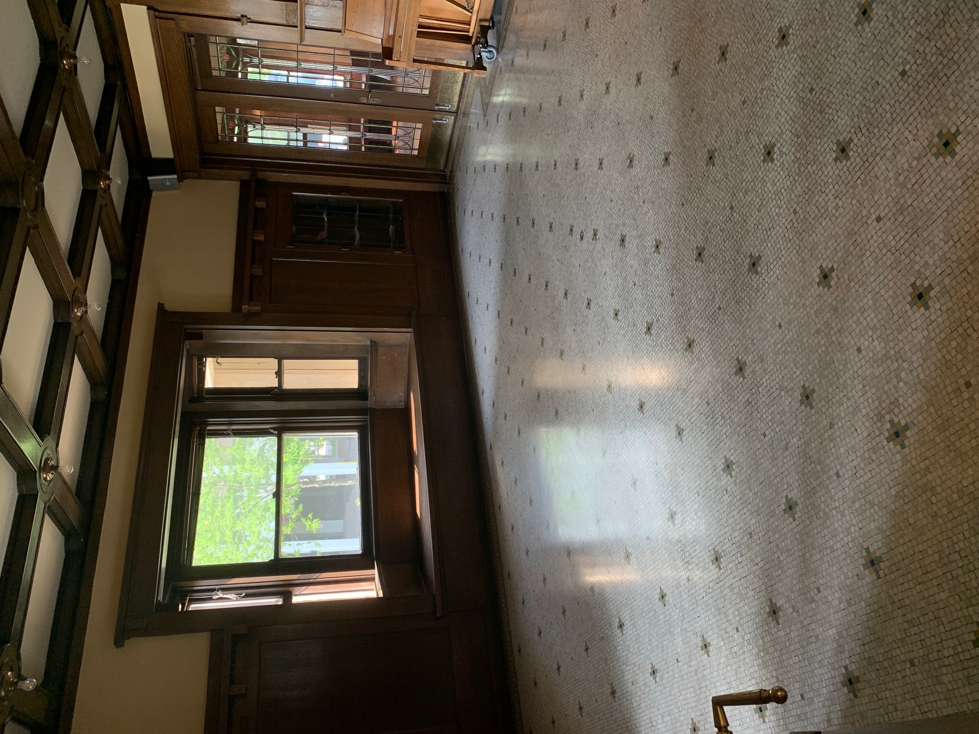 Grand entryway with mosaic tile floor and wood-framed windows.